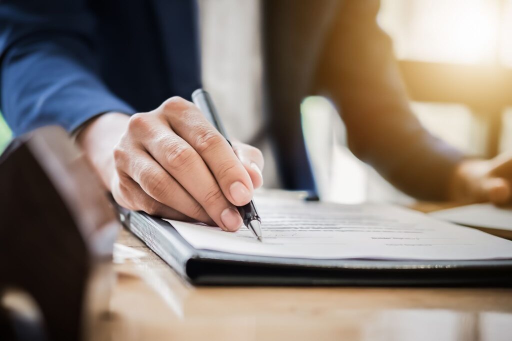 A homeowner signing a solar panel contract cancellation agreement with solar panels in the background.