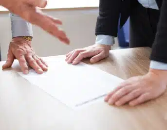 Close-up of hands reviewing a residential solar agreement for permanent cancellation; SCRC experts helping a homeowner terminate a solar loan.